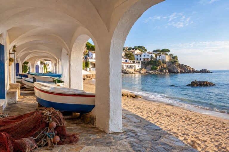 Witte vissersarcades langs het strand Port Bo in Calella de Palafrugell aan de Costa Brava.