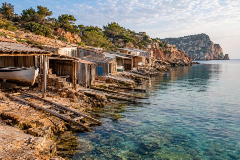 Houten vissershutten en boothellingen aan het heldere water van Sa Caleta op Ibiza
