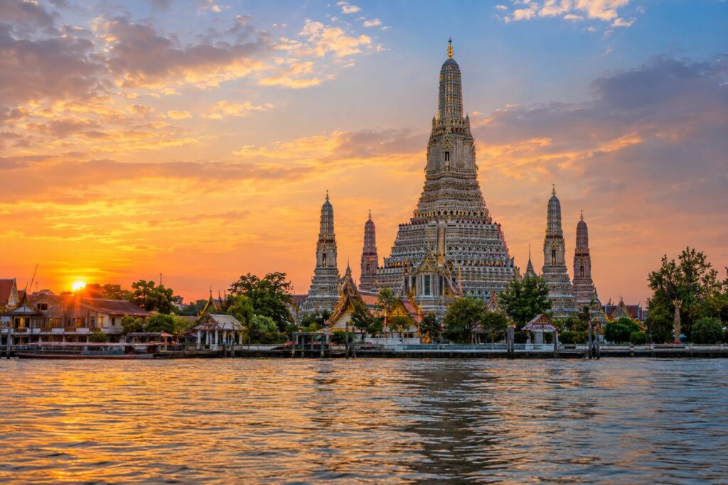 De met porselein versierde toren van Wat Arun weerspiegeld in de Chao Phraya-rivier