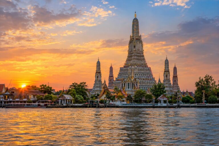 De met porselein versierde toren van Wat Arun weerspiegeld in de Chao Phraya-rivier
